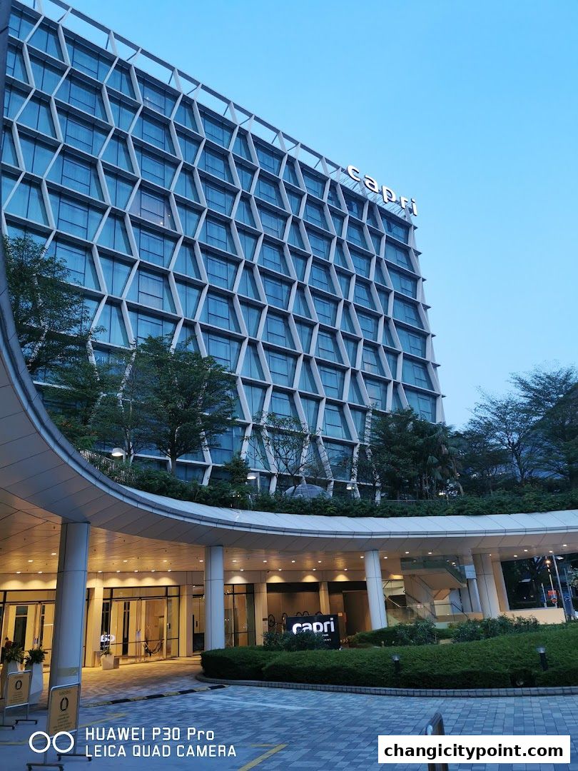 Modern building exterior with a curved walkway and green landscaping.
