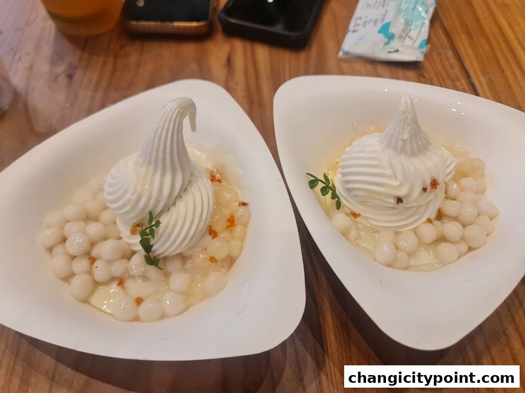 Two elegant white bowls filled with creamy dessert and small white pearls, garnished with a swirl of cream.