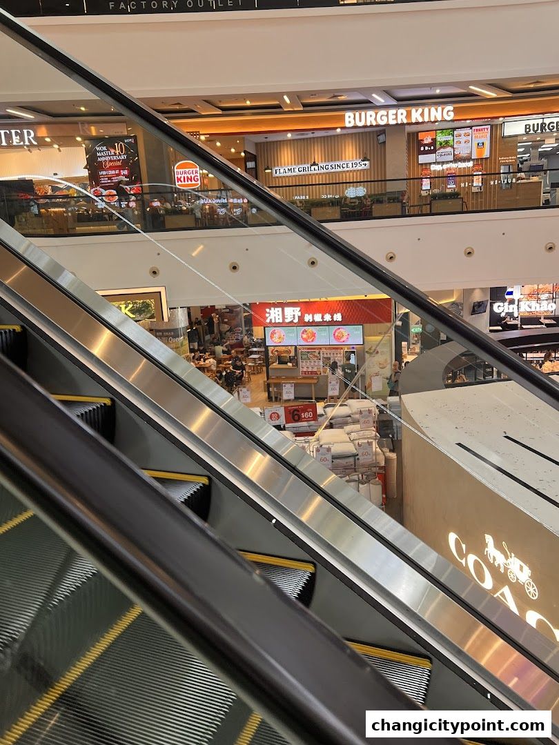 View of a shopping mall interior with escalators, Burger King, and other shops.