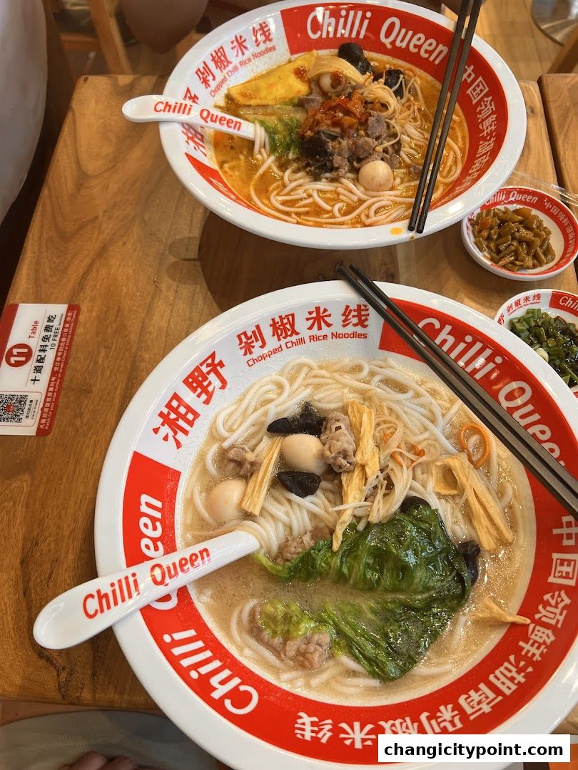 Two bowls of delicious rice noodle soup with various toppings and chopsticks.