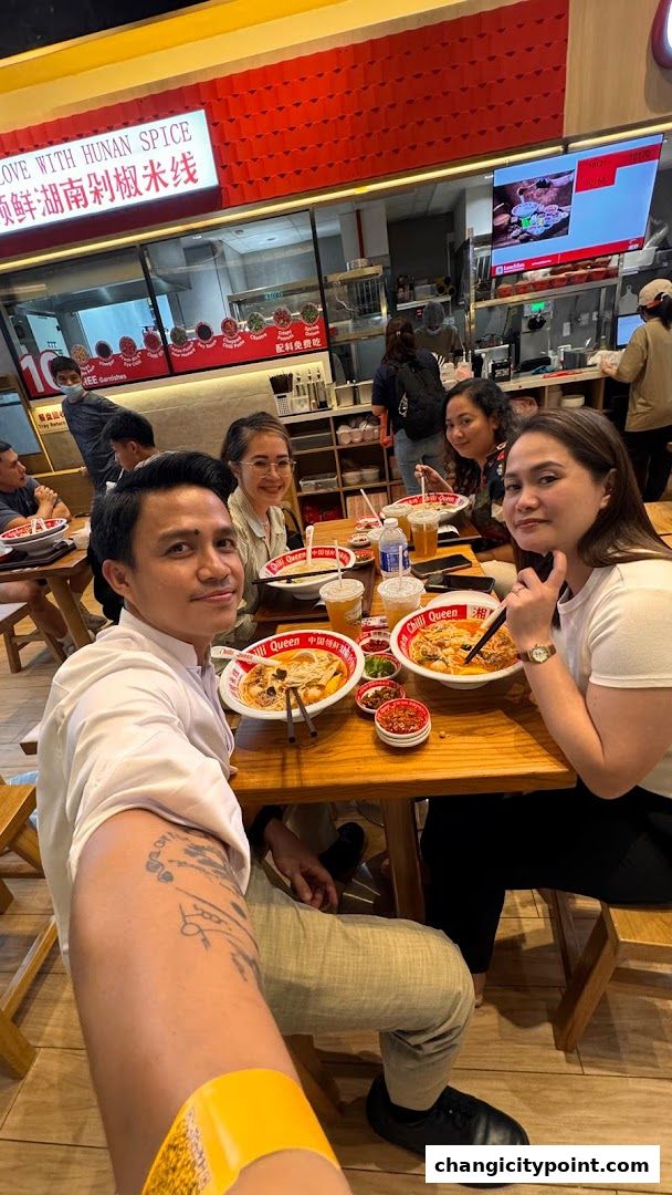 People enjoying bowls of rice noodles at tables inside Chilli Queen.