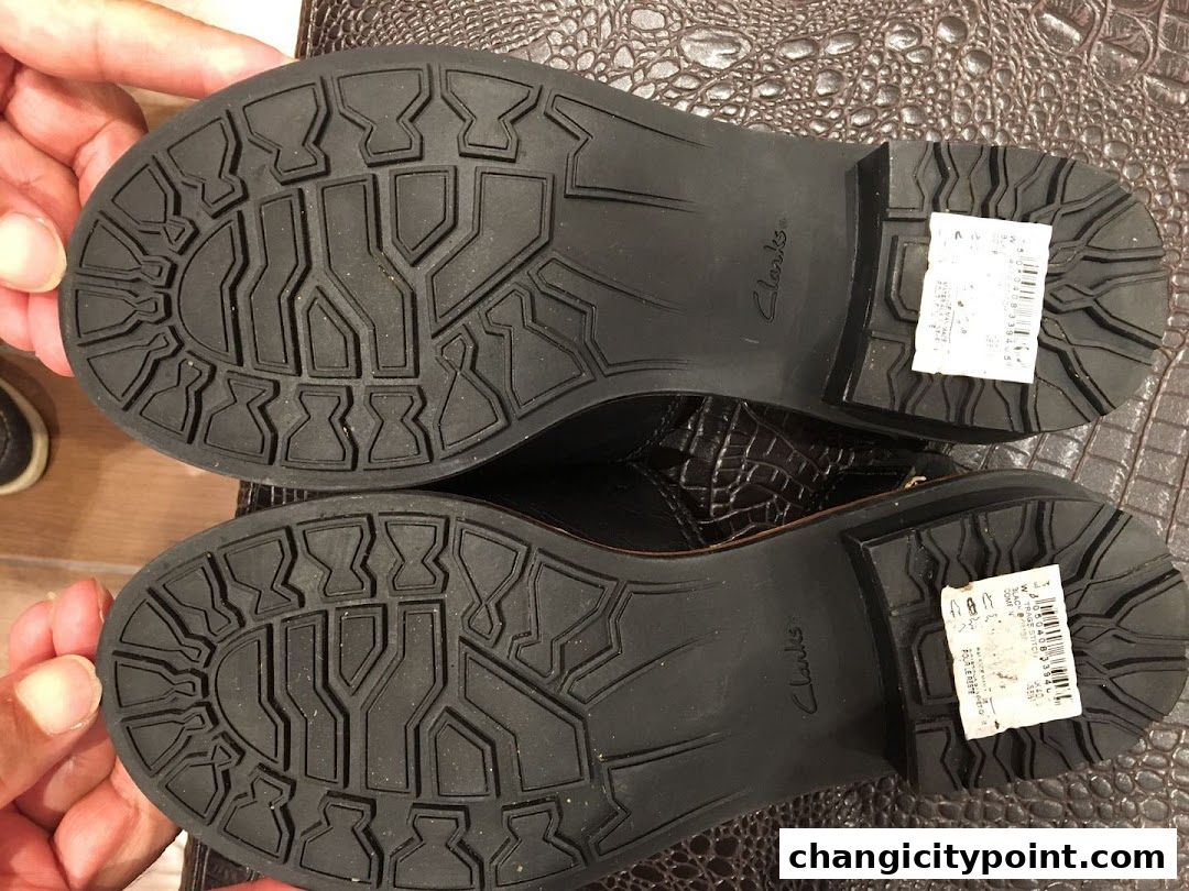 Close-up of the soles of two brown Clarks boots with textured patterns.