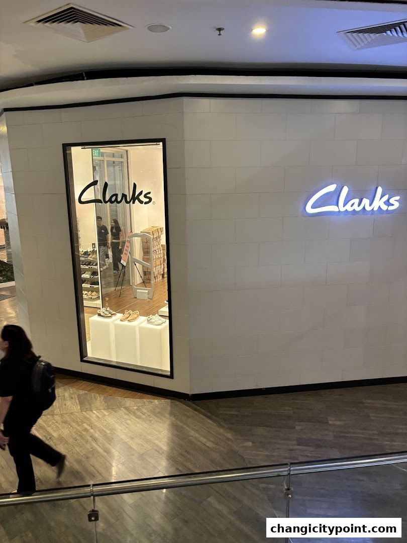The exterior of a Clarks Outlet store with a window display and neon signage.