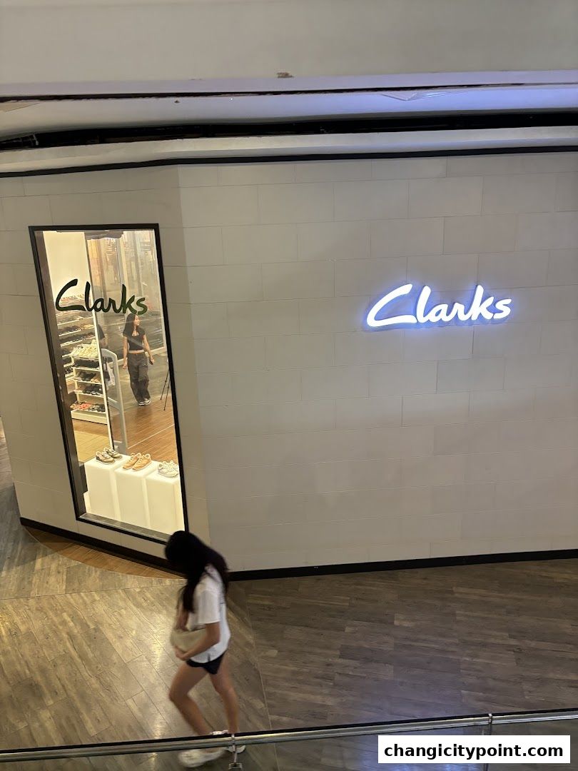 A person walks past the Clarks Outlet store with its illuminated logo and display window.