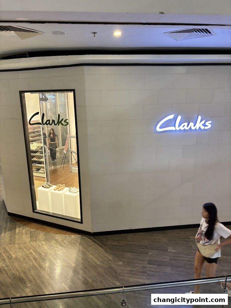 The exterior of a Clarks Outlet store with a display window and neon signage.