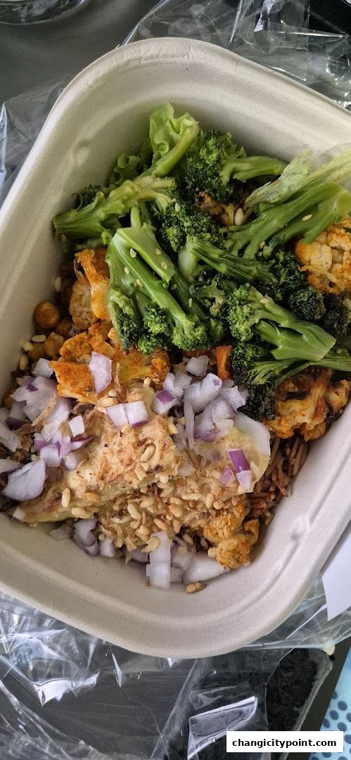 A close-up of a healthy salad bowl with broccoli, cauliflower, chickpeas, and red onions.