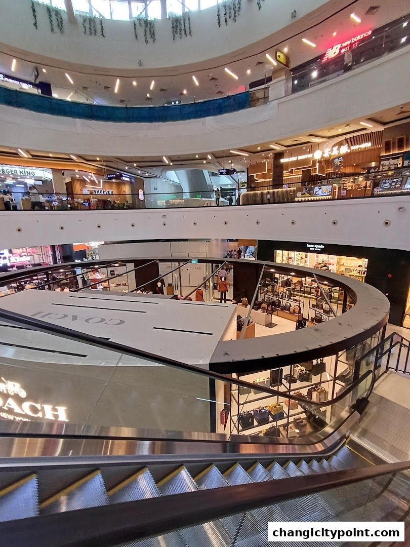 Coach Outlet store interior with bags displayed on shelves and escalators in the foreground.