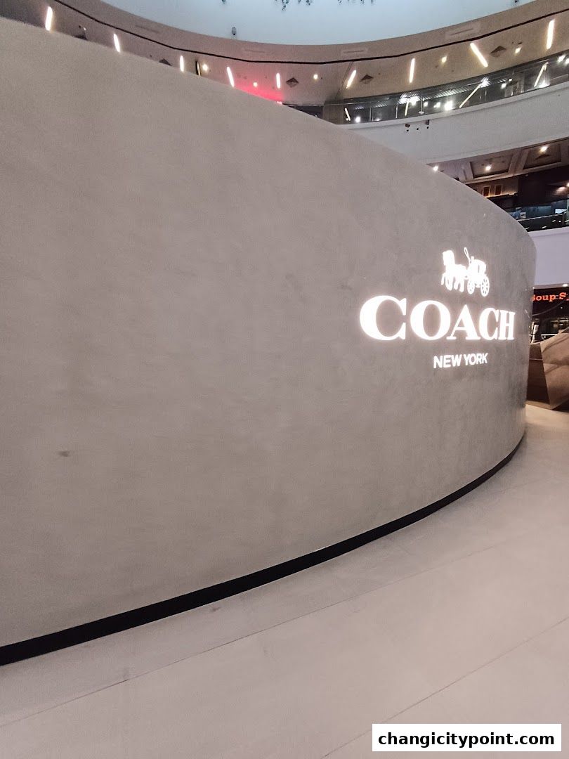 The illuminated Coach New York logo is displayed on a curved, modern store facade.