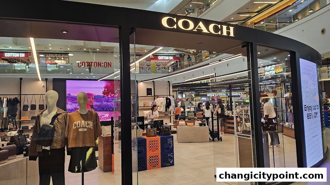 Coach Outlet store entrance with mannequins displaying apparel and bags, and a digital screen showing a promotion.