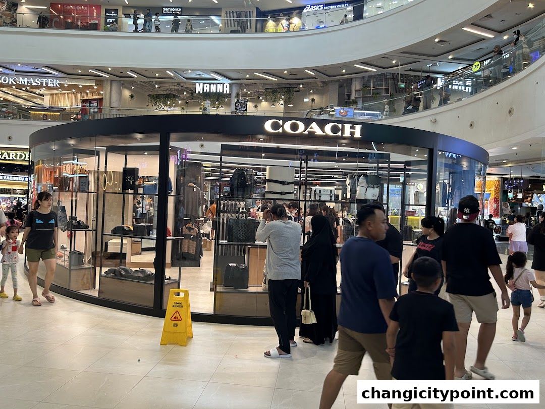 Coach Outlet store entrance with display windows showcasing handbags and apparel.