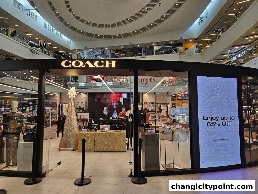 Coach Outlet store entrance with mannequins, displays, and a large digital advertisement.