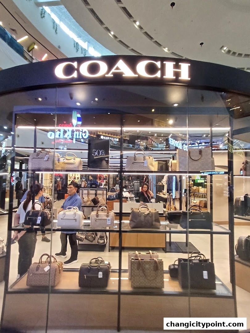 Coach Outlet store window display featuring various handbags and a '50%' sale sign.