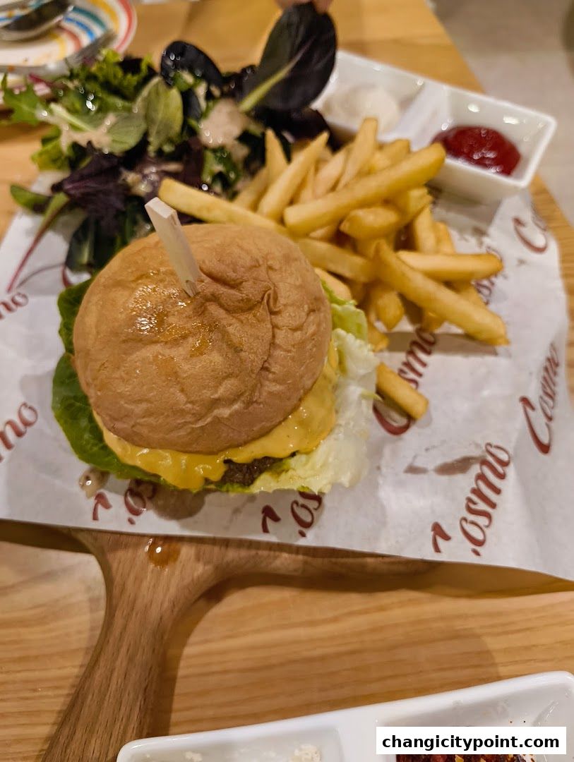 A delicious burger with fries and salad served on a wooden board.