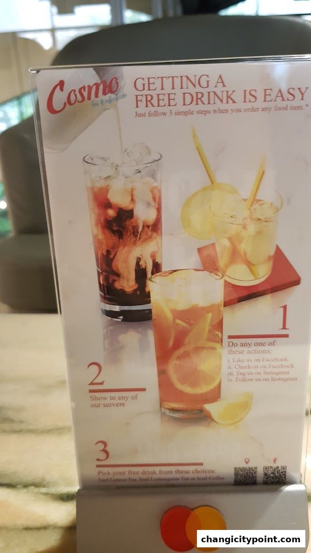 A sign promoting a free drink offer at Cosmo Bar & Cafe with instructions and drink images.