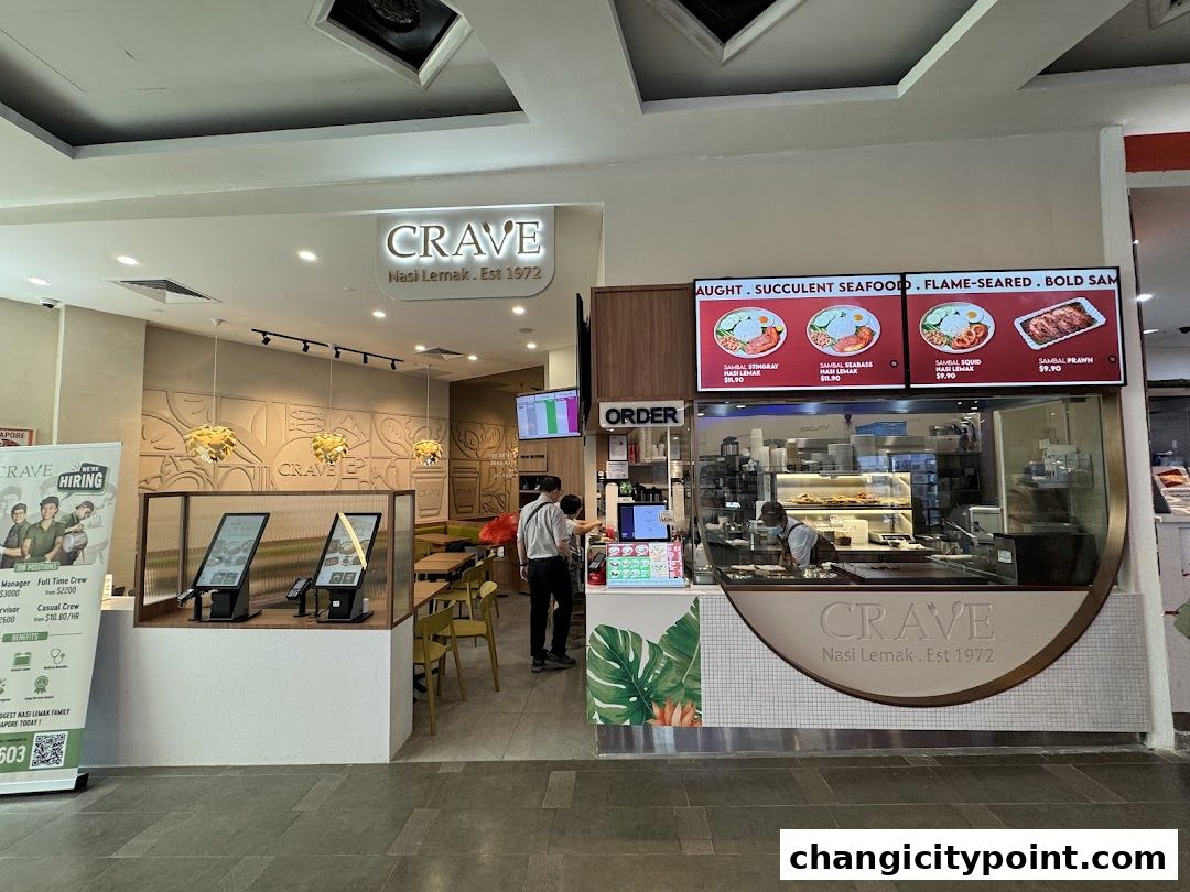 The entrance of Crave Nasi Lemak restaurant with a menu display and ordering kiosks.
