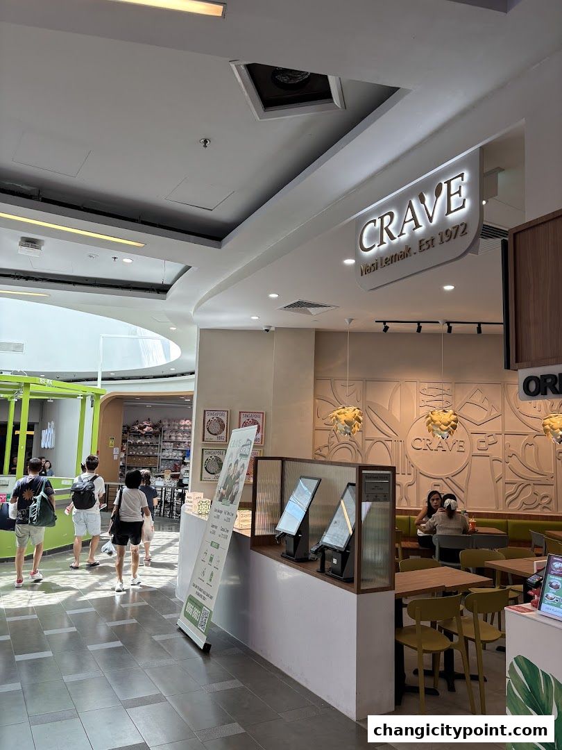 Interior view of Crave Nasi Lemak restaurant with seating and ordering kiosks.