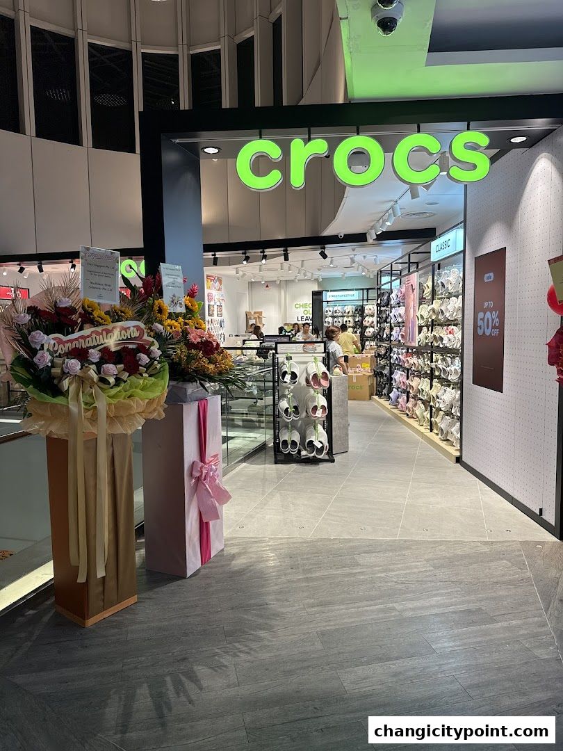 The entrance to a Crocs Outlet store displaying various footwear and a sale sign.