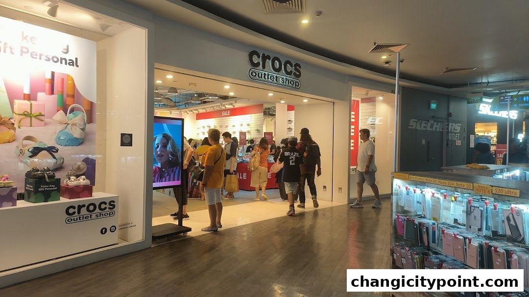 The entrance of a Crocs Outlet shop with a display window and people browsing inside.
