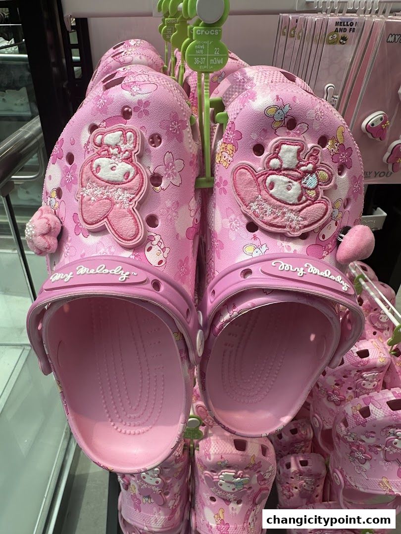 Pink Crocs featuring My Melody and cherry blossom designs are displayed for sale.