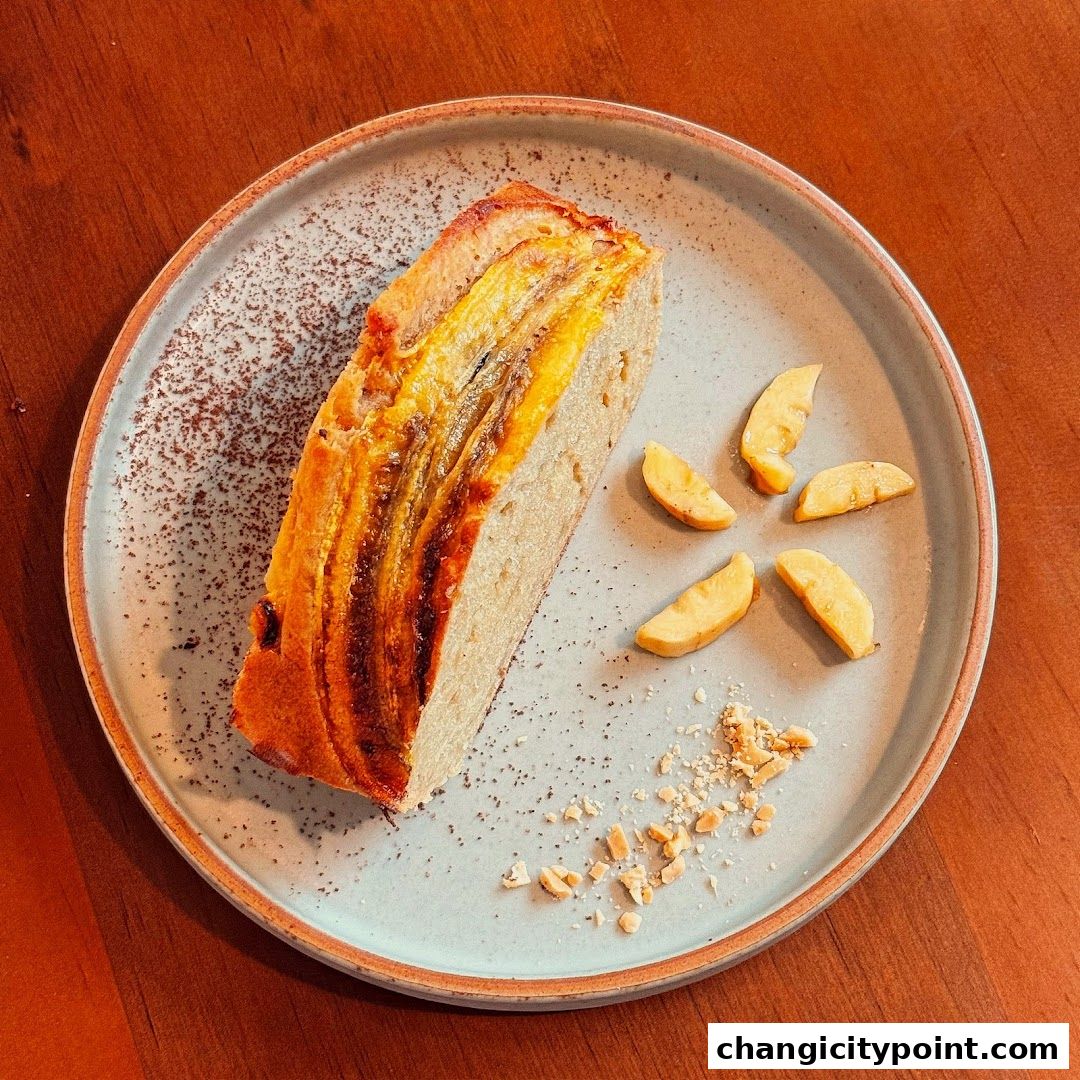 A slice of banana bread served on a plate with apple slices and chopped nuts.