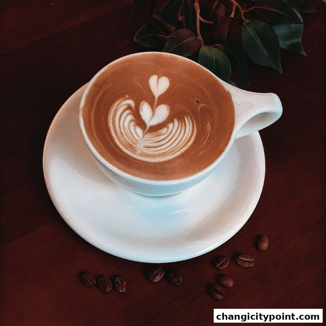 A beautifully crafted latte with intricate foam art, served in a white cup and saucer.