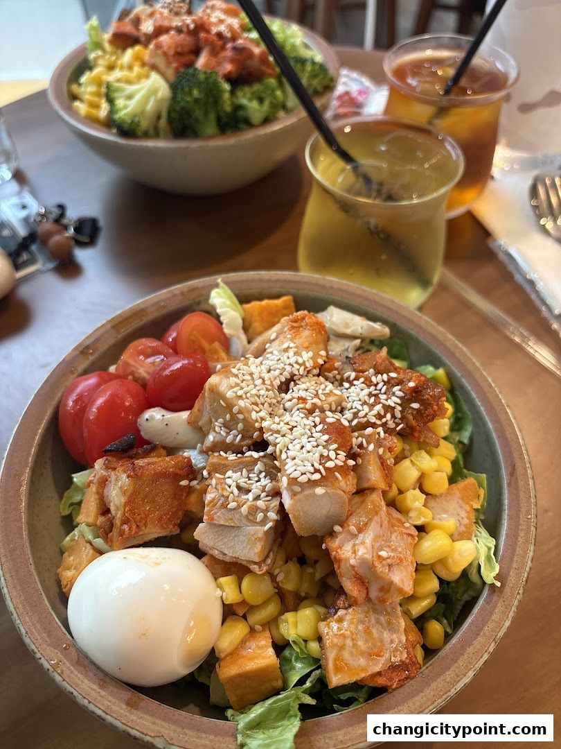 Two bowls of salad with chicken, corn, tomatoes, and a hard-boiled egg, served with iced tea.