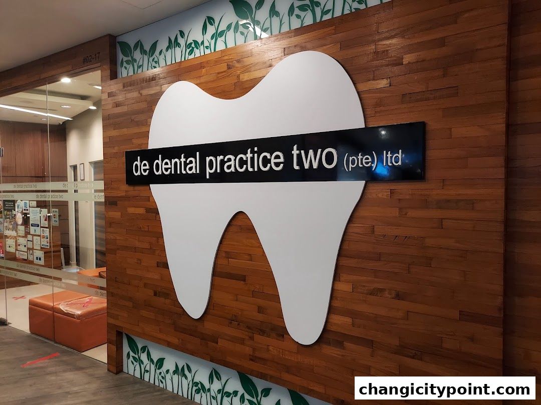 The entrance of De Dental Practice Two Ltd, featuring a large tooth logo and wooden paneling.