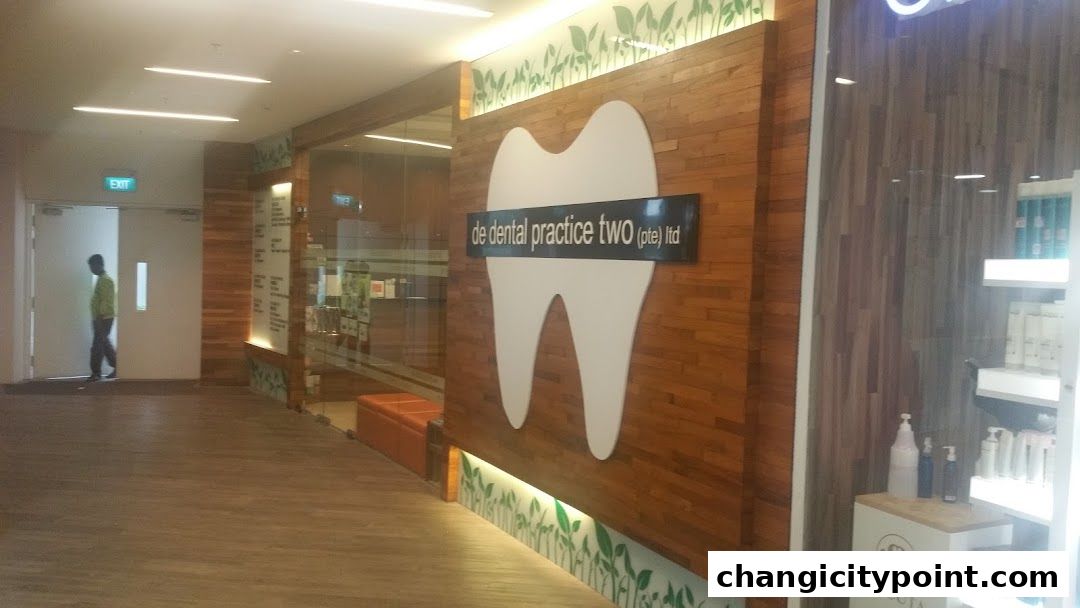 The exterior of De Dental Practice Two Ltd, featuring a large tooth logo and wooden paneling.