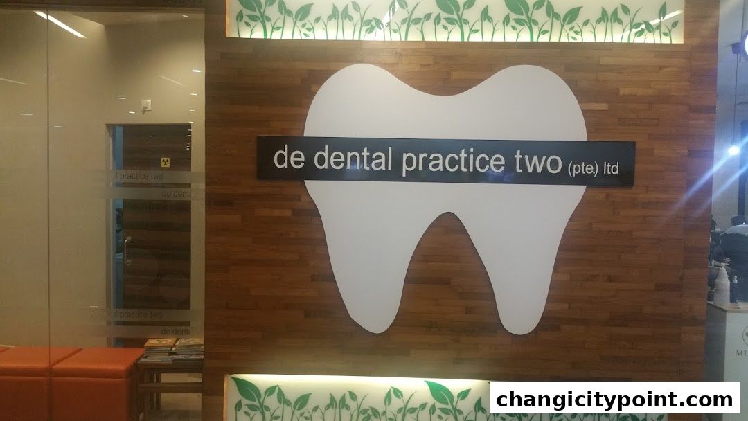 The entrance of De Dental Practice Two Ltd, featuring a large tooth logo and wooden paneling.