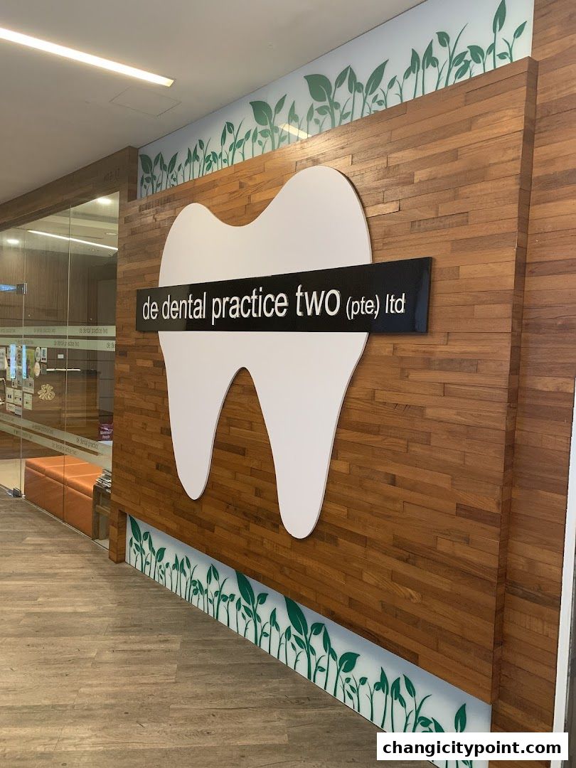 The entrance of De Dental Practice Two Ltd, featuring a large tooth logo and wooden paneling.