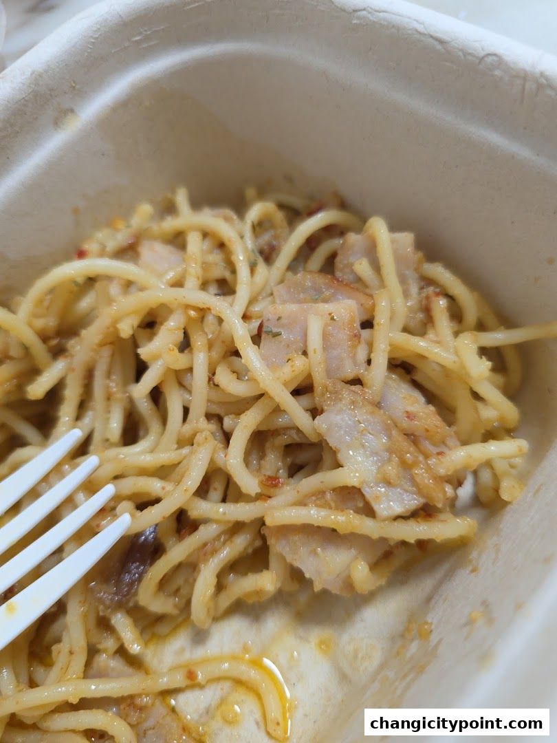 A close-up shot of spaghetti with meat in a takeaway container with a fork.