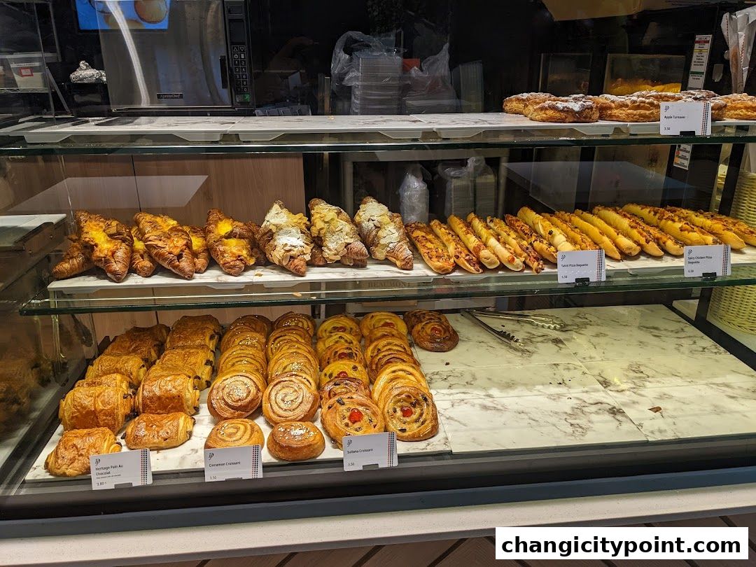 A display case filled with various pastries, croissants, and baguettes at Delifrance.