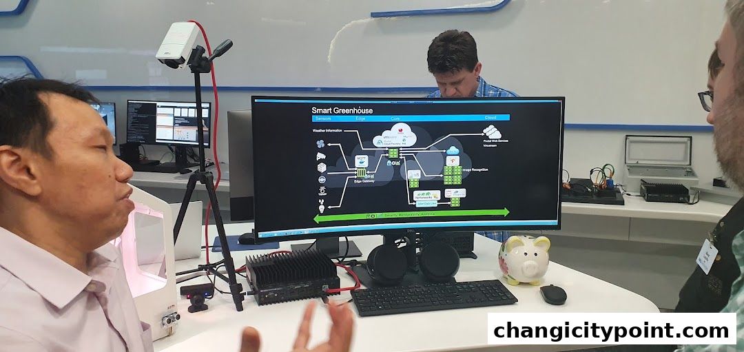 People gathered around a computer displaying a smart greenhouse system diagram.