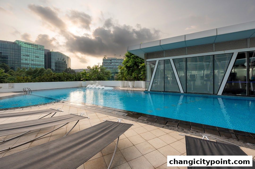 An outdoor swimming pool with lounge chairs and a modern gym facility in the background.