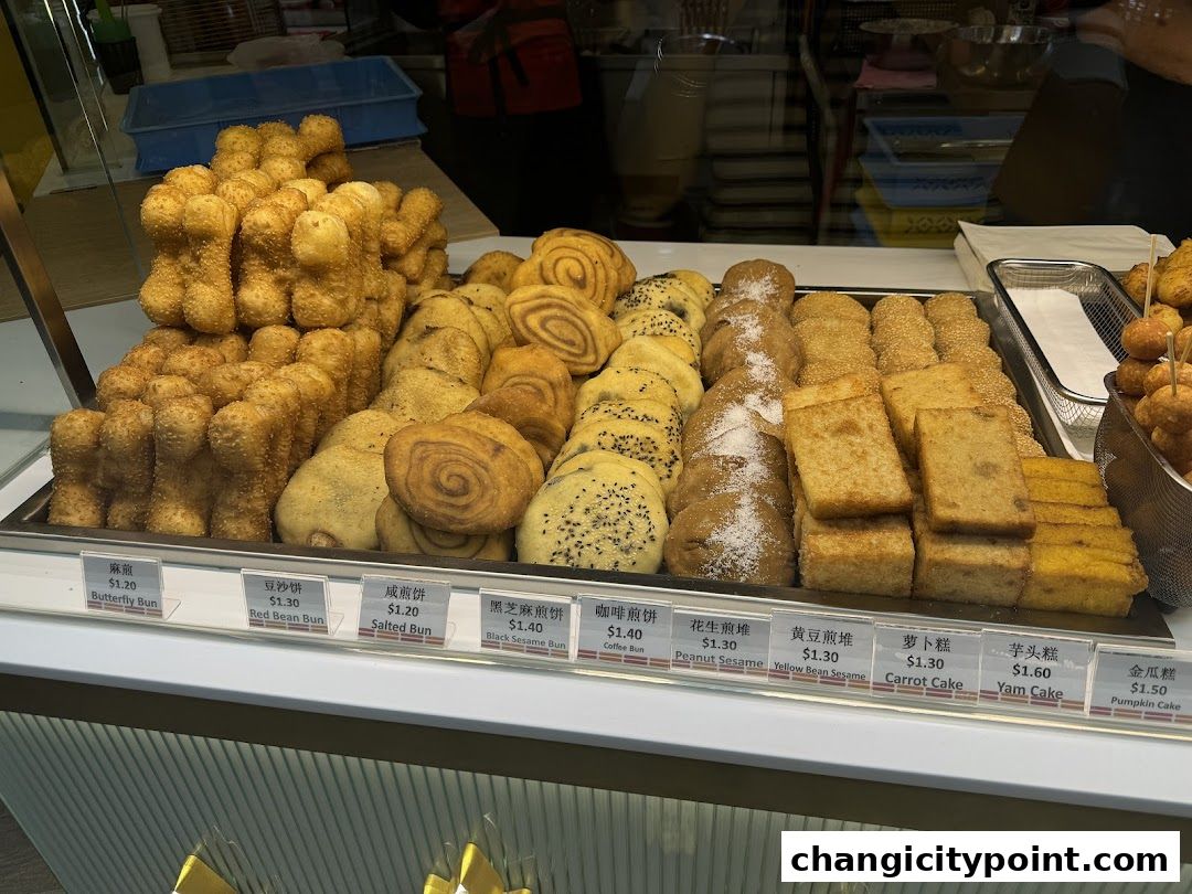 A display of various baked goods and pastries with price labels in a shop window.