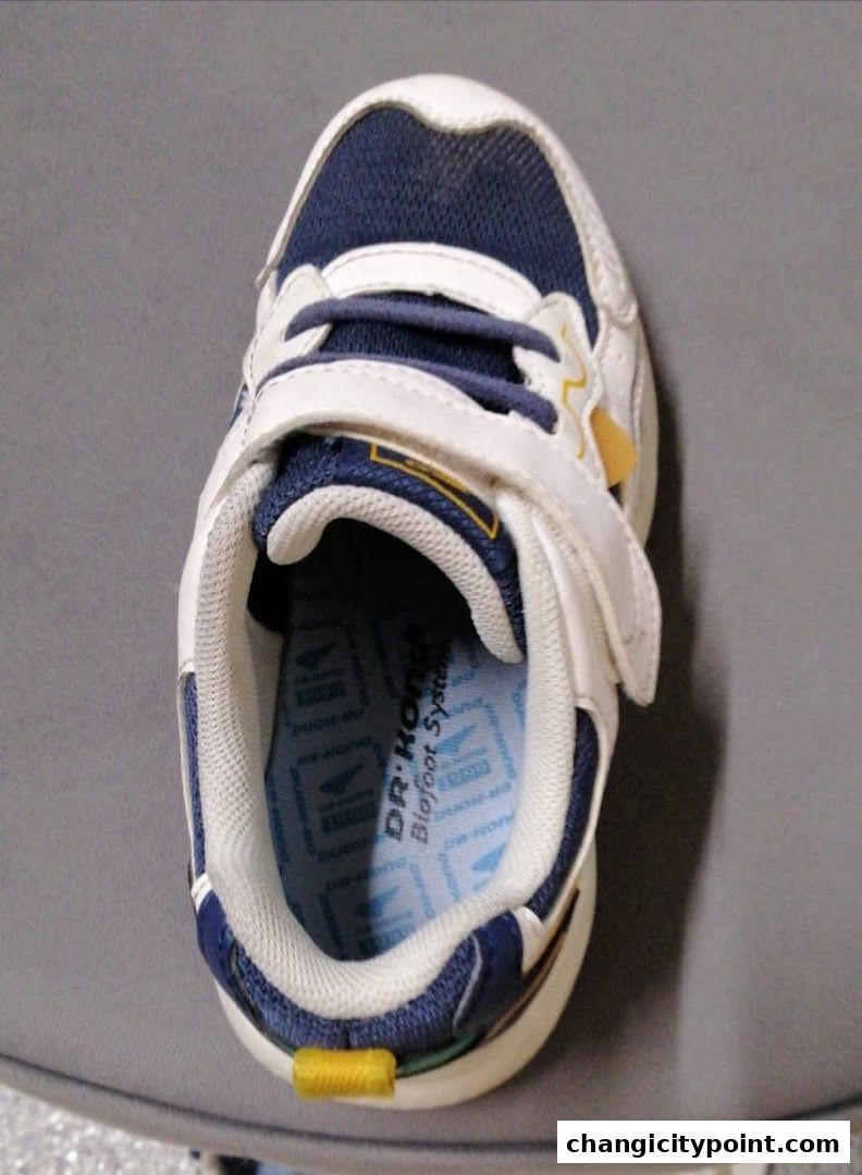 A close-up view of a child's white and blue sneaker with the Dr. Kong Biofoot System insole.