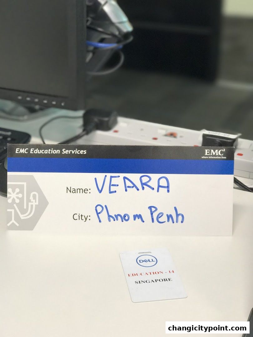 A sign for EMC Education Services with handwritten name and city, and a Dell badge.