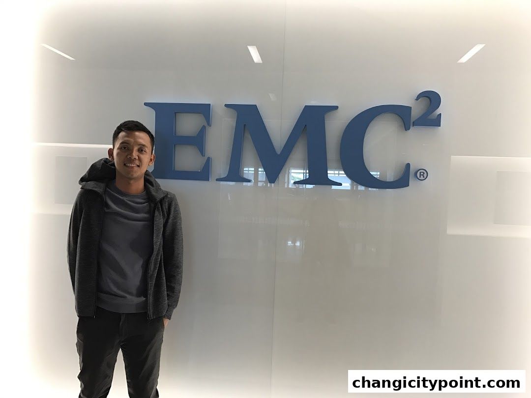 A man stands in front of the EMC Computer Systems logo on a white wall.