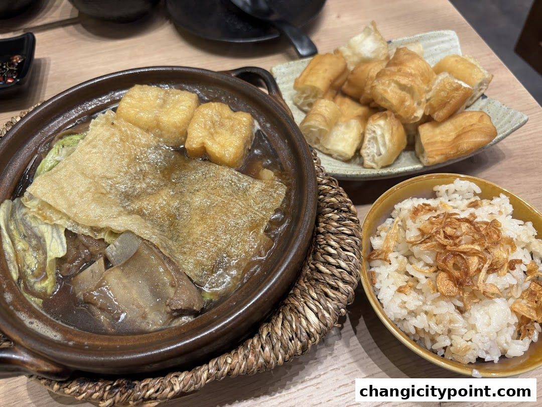 A close-up of a hearty bowl of Bak Kut Teh with fried dough sticks and rice.