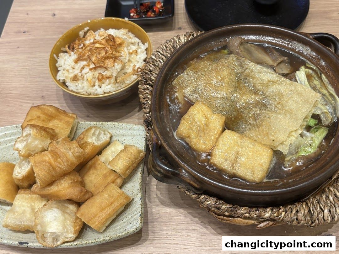 A steaming bowl of Bak Kut Teh with rice and fried dough sticks.