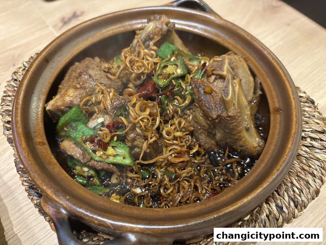 A steaming clay pot filled with tender pork ribs, noodles, and okra.