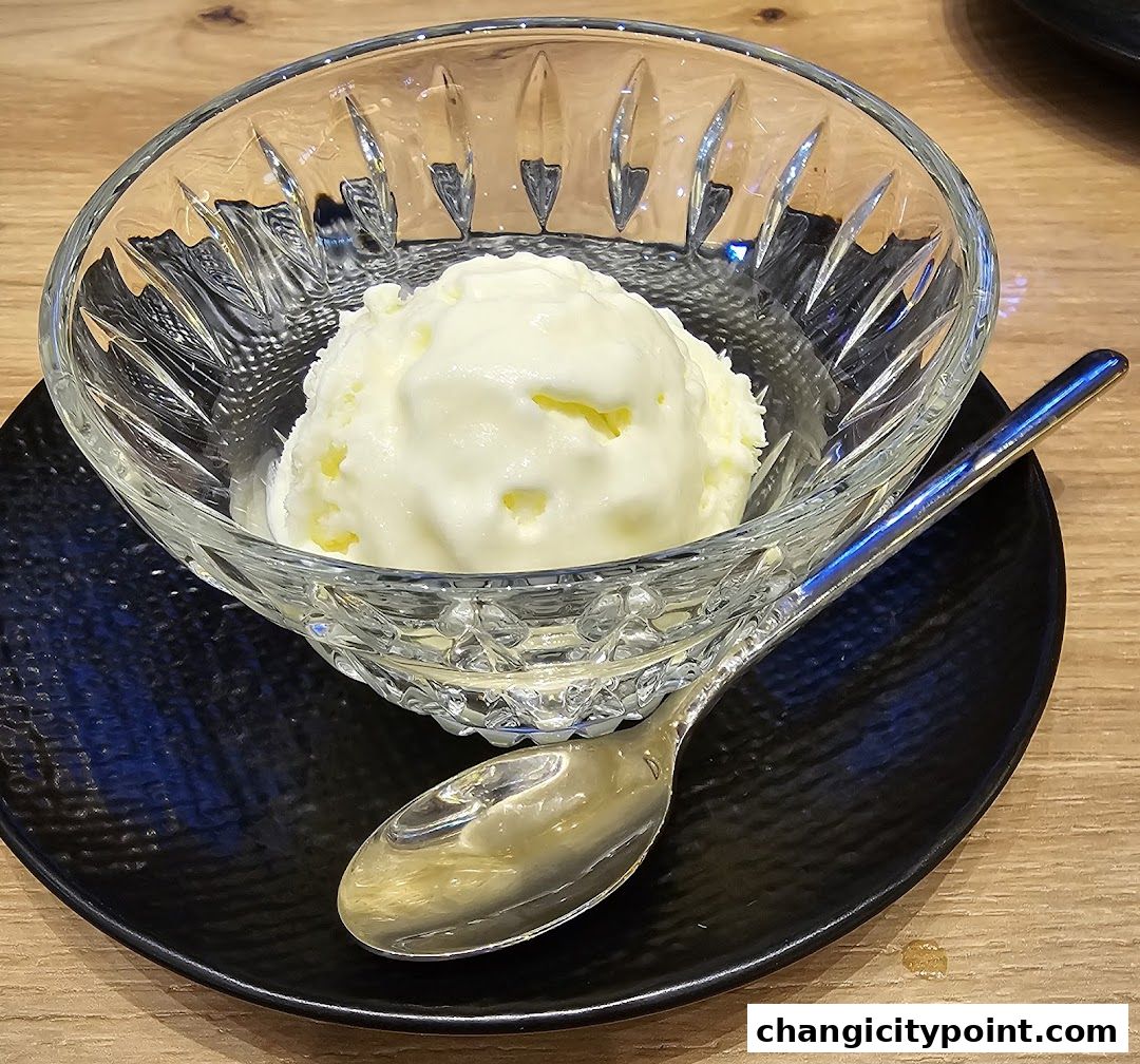 A scoop of creamy ice cream served in a decorative glass bowl with a spoon.