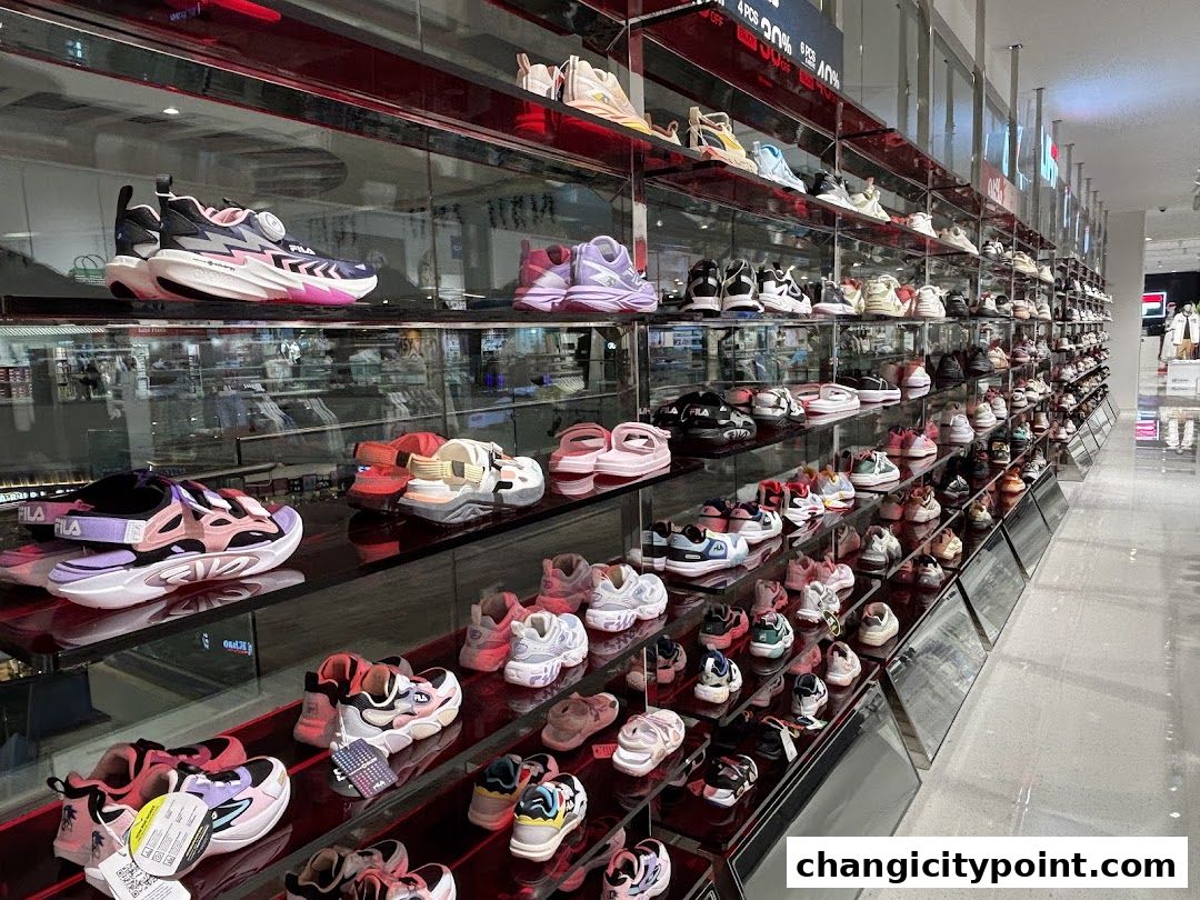 A wide display of Fila sneakers and sandals on shelves in a retail store.