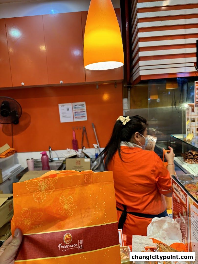 A person in an orange uniform works behind the counter at Fragrance Bak Kwa.