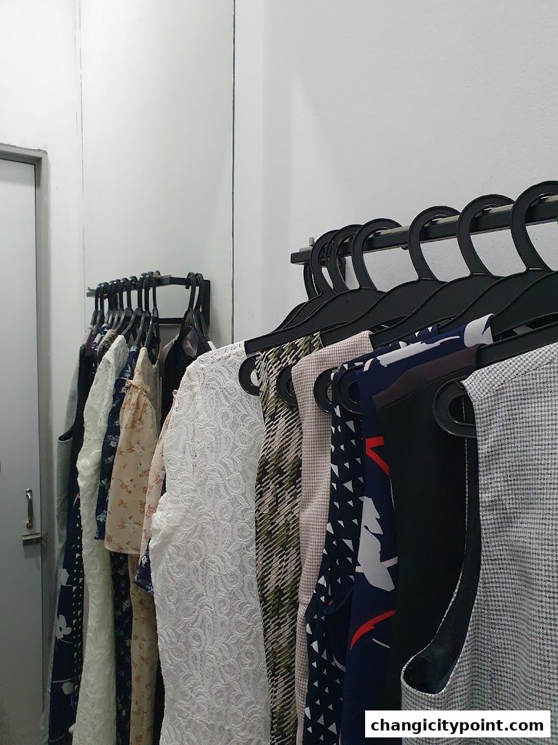 A rack of diverse women's clothing, including dresses and tops, displayed in a retail setting.