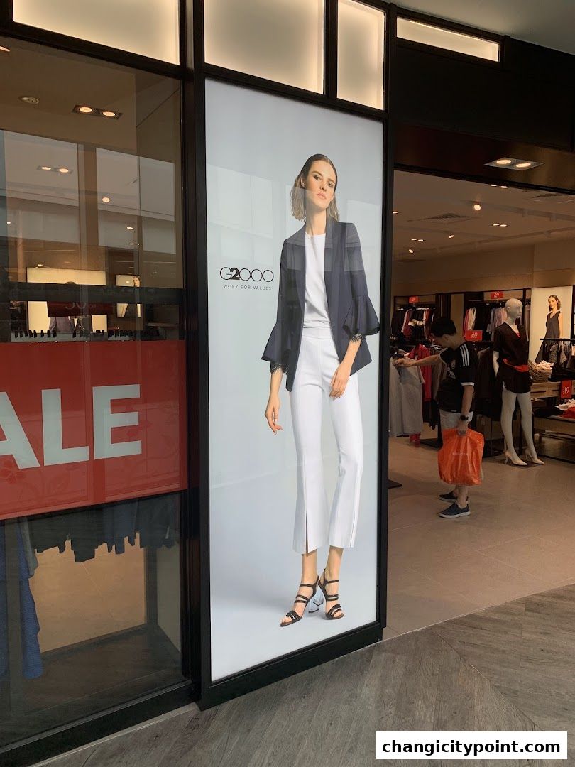 G2000 shop front display featuring a model in stylish office wear and a sale sign.