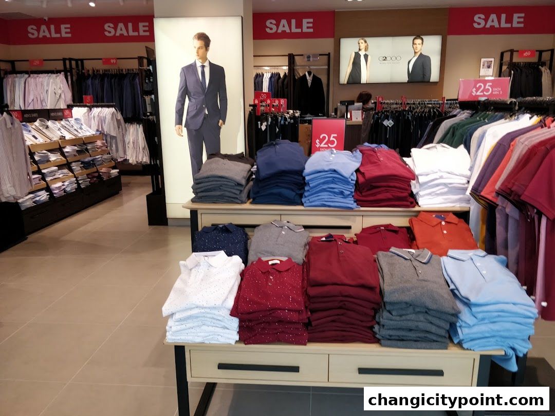 Interior of a G2000 clothing store with sale signs and stacks of polo shirts.