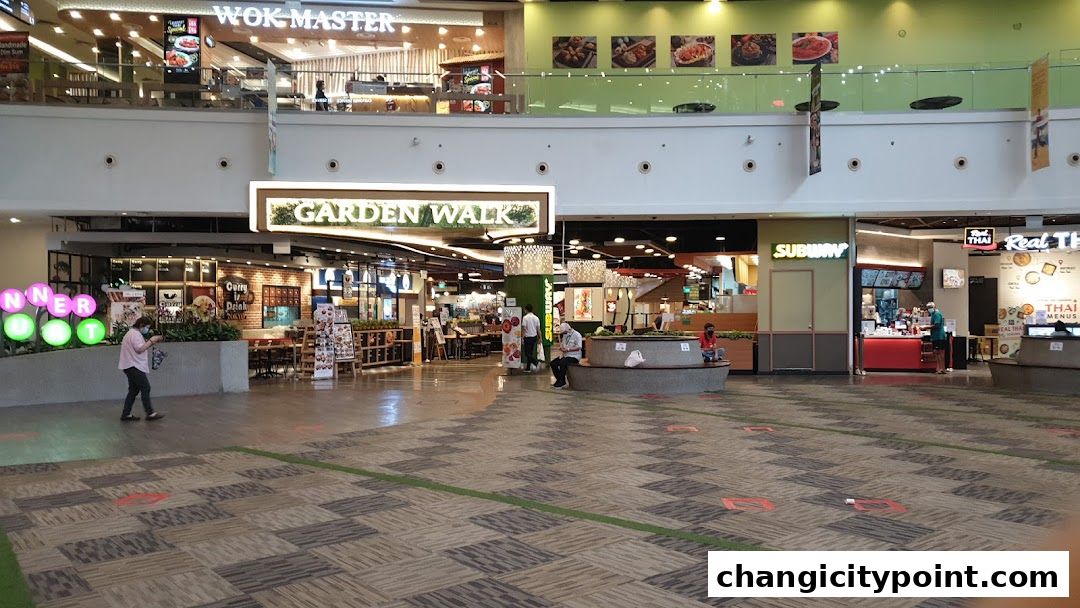 A wide view of a shopping mall food court with various restaurants and seating areas.