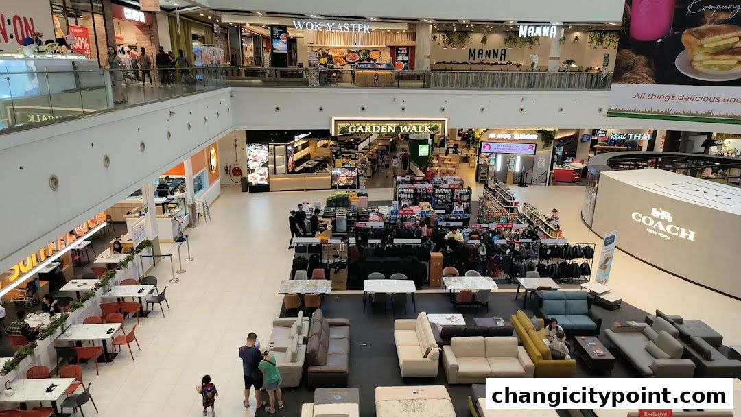 A wide view of a shopping mall interior with various shops and seating areas.