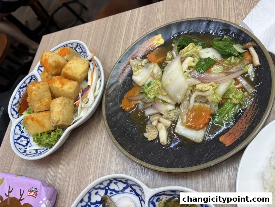 Delicious Thai dishes, including fried tofu and stir-fried vegetables, served on a wooden table.